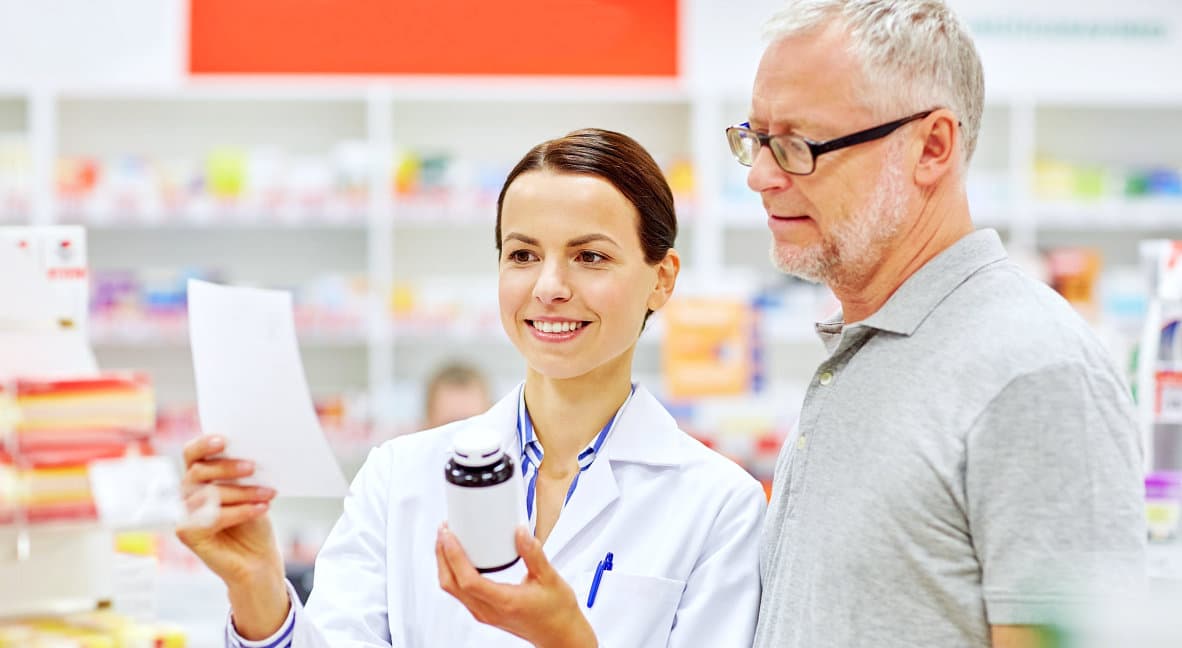 female pharmacist showing medicine to senior man